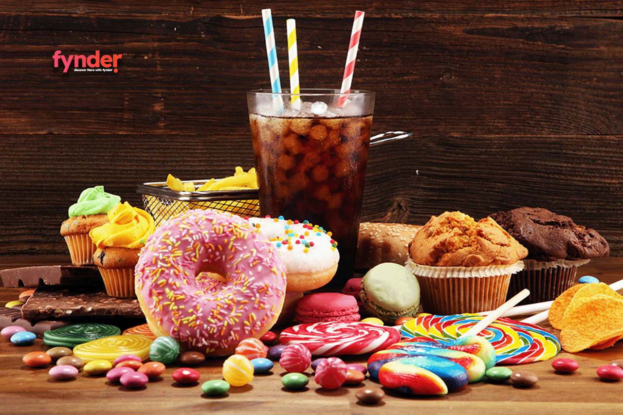 This is an image of an assortment of junk food include cake, crips and glass of carbonated drink